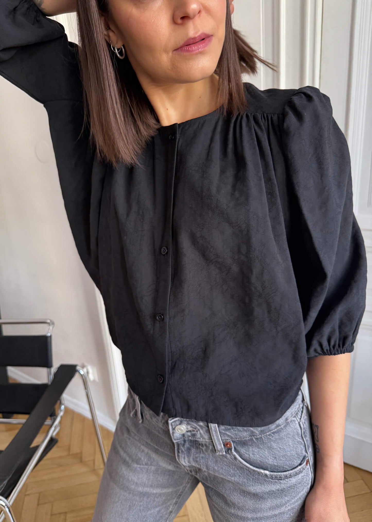 Koszula Nell ASIDE, czarna z żakardowej tkaniny w kwiaty, bufiastym rękawem, zapinana na guziki.